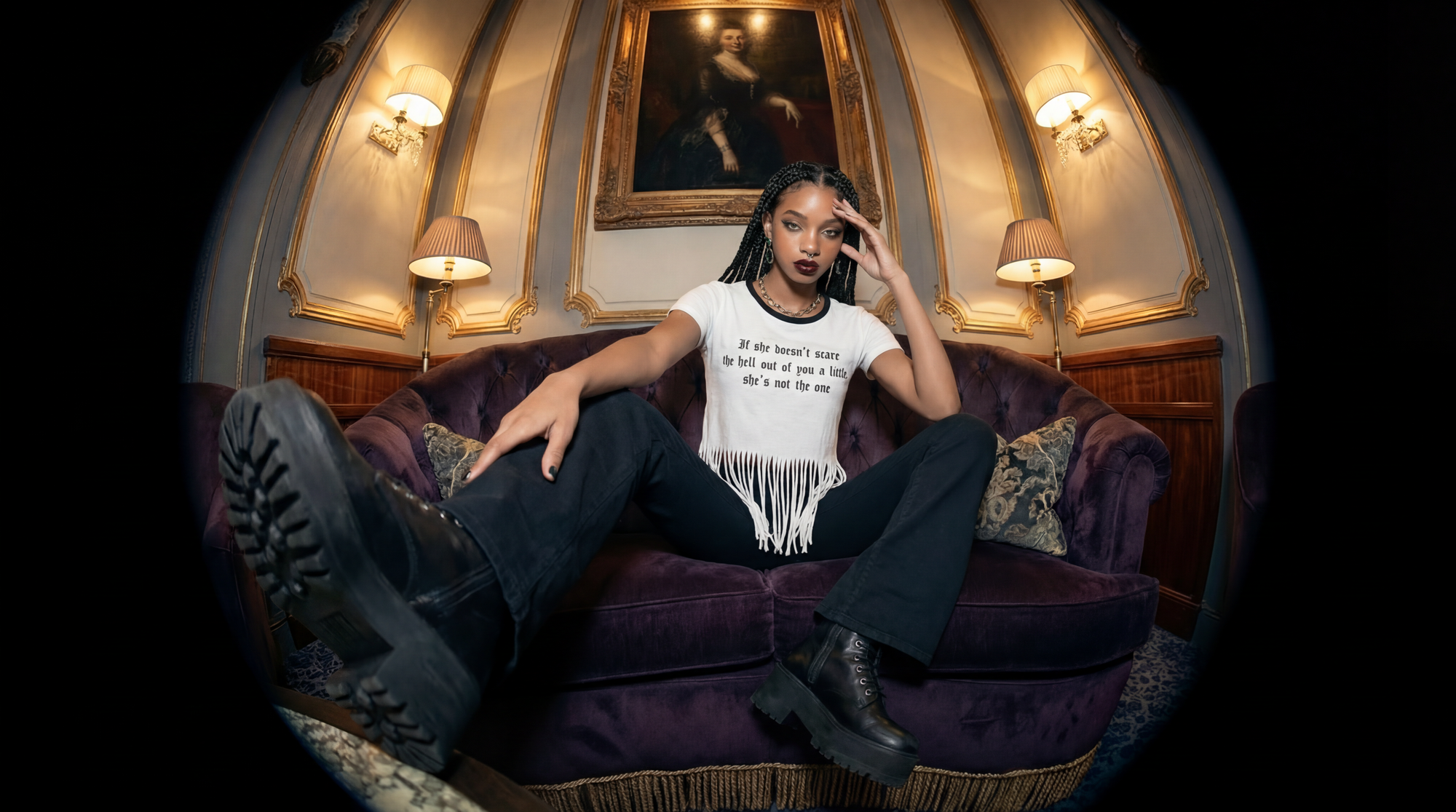 Woman sitting on a purple couch in an ornate room with a painting on the wall.